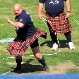 Burly men hurl heavy items throughout the area in a display of concentration and strength.